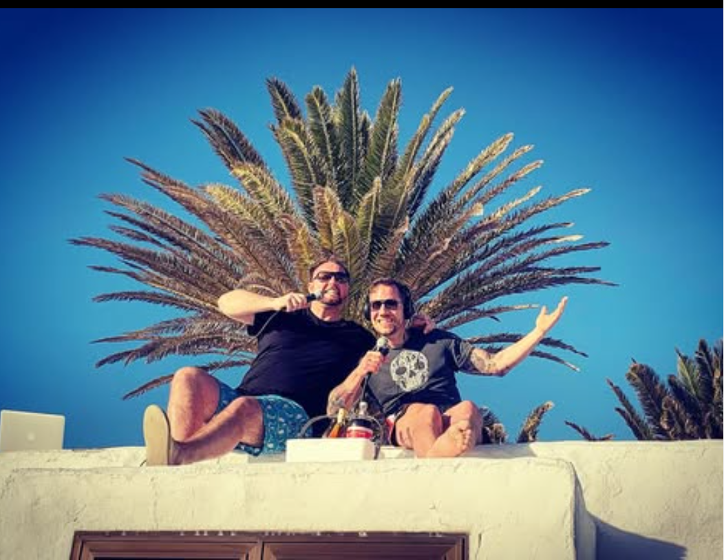 Olaf und Roland mit Mikrofonen vor einer Palme